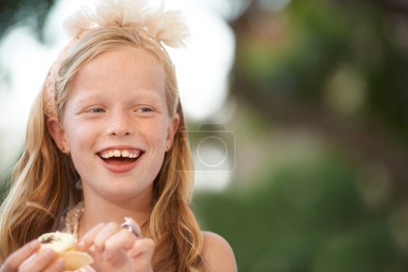 Téléchargez les photos : Enfant, fille et manger cupcake ou sourire en plein air pour la nourriture d'anniversaire ou de célébration, dessert ou bonbons. Personne féminine, enfant heureux et collation sucrée à l'événement de jardin pour la joie affamée ou traiter le repas, la fête ou le plaisir. - en image libre de droit