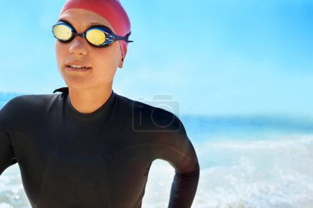 Téléchargez les photos : Sports, lunettes et nage femme sur la plage avec ciel bleu pour le triathlon, la course ou l'entraînement de compétition. Nageuse, athlète ou personne dans l'océan ou la mer pour l'entraînement physique ou l'exercice physique pour la santé. - en image libre de droit