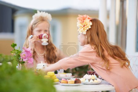 Photo for Girls, children and friends at tea party outdoor for fantasy play in garden for cake, birthday or game. Kids, youth and fancy dress up in nature for summer bonding in backyard, beverage or preschool. - Royalty Free Image