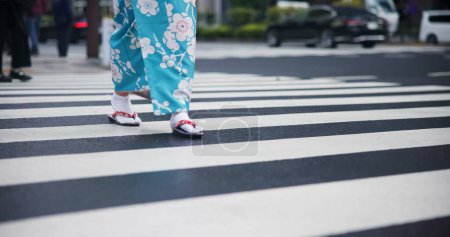 Téléchargez les photos : Femme japonaise, pieds et voyage en kimono en ville, voyage et bien-être pour la célébration du patrimoine. Personne, marches et vêtements traditionnels à Tokyo pour les vacances et traversée piétonne à la mode japonaise. - en image libre de droit