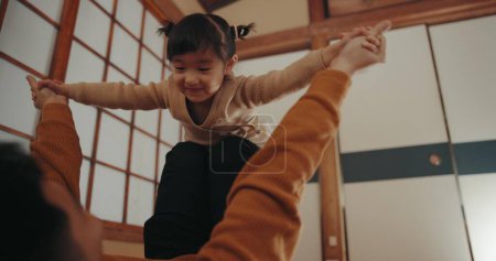 Foto de Bebé, juego de avión y mamá en una casa familiar japonesa con niño pequeño, amor y diversión feliz. Casa, madre y niña con sonrisa, sala de estar y volar con la unión junto con un niño y mamá. - Imagen libre de derechos