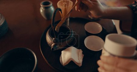 Photo for Hands of woman in traditional Japanese matcha, drink and relax with mindfulness, respect and service. Girl at calm tearoom with teapot, zen culture and ritual at table for tea ceremony from above - Royalty Free Image
