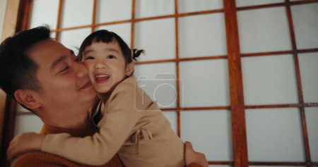 Foto de Papá, hogar y abrazo con hija, feliz y sonriente de alegría, recuerdos japoneses e infantiles. Padre, niña y diversión con el niño, piso de la sala de estar y crianza juntos para la alegría, despreocupado y alegre. - Imagen libre de derechos