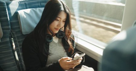 Téléchargez les photos : Japon femme, Voyage et train sur smartphone, les médias sociaux et les transports en commun sur la balle de métro. Personne, téléphone portable et en ligne sur un véhicule rapide pour le week-end et de se rendre à Tokyo pour l'aventure. - en image libre de droit