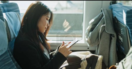 Photo for Japanese woman, reading and smartphone on train, social media and public transportation on metro bullet. Person, cellphone and online on fast vehicle on weekend trip and commute in tokyo on adventure. - Royalty Free Image
