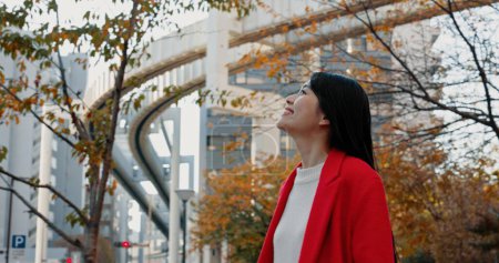 Foto de Pensando, mujer japonesa y al aire libre en la ciudad para viajar en tren en otoño con árboles y felicidad. Parque, la naturaleza y la persona de negocios en Tokio para desplazarse por la mañana en metro transporte. - Imagen libre de derechos