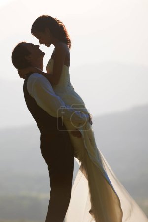 Photo for Groom lift bride, wedding outdoor and hug with love for commitment in marriage. Man, woman and happiness, celebration and social event with trust and loyalty, romance and life partner in nature. - Royalty Free Image
