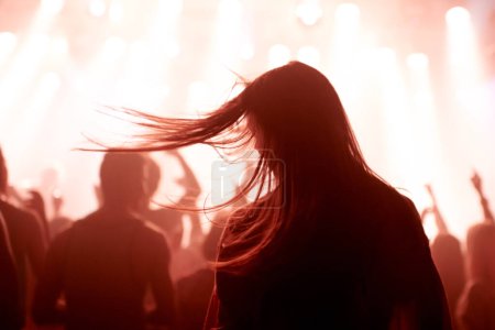 Person, dancing and crowd or concert silhouette for live music performance or festival, rock or friends. Audience, club and red lights for celebration rave or band sound as partying, weekend or night.