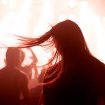 Person, dancing and crowd or concert silhouette for live music performance or festival, rock or friends. Audience, club and red lights for celebration rave or band sound as partying, weekend or night.