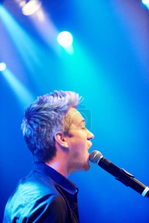 Photo for Man, singing and performing at night, concert and stage for music festival, party and entertaining crowd. Microphone, musician and rave on weekend, event and rockstar in club for celebration. - Royalty Free Image