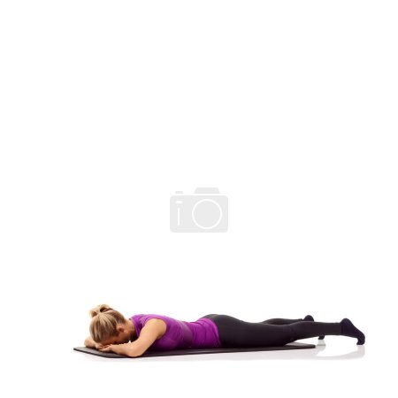 Téléchargez les photos : Tapis de yoga, santé et détente avec une femme en studio pour l'étirement, l'exercice et le bien-être. Entraînement, fitness et auto-soin avec une femme sur le sol de fond blanc pour pilates, corps ou espace de maquette. - en image libre de droit
