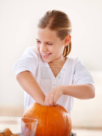 Photo for Girl, child and happy with pumpkin for halloween, celebration or decoration in kitchen of apartment or home. Kid, face and smile with vegetable for preparation, holiday or creative event in house. - Royalty Free Image