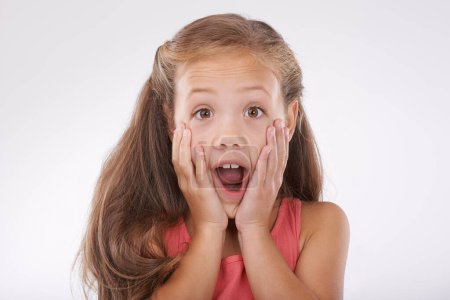 Photo for Girl, child with face and surprise, shock in studio with reaction or facial expression to drama and gossip. Wow, emoji and fear with story, info or announcement with portrait on white background. - Royalty Free Image