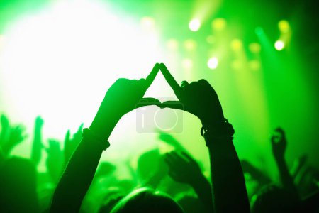 Photo for Triangle hands, neon and person in concert audience for music, festival or performance on stage. Party, psychedelic and green light with crowd of people outdoor for event, disco or club celebration. - Royalty Free Image