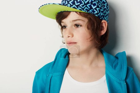 Photo for Thinking, fashion and young child in a hoodie in studio isolated on a white background. Trendy style, cool kid and cap of boy or model in a hat, casual clothes and serious on a backdrop in Sweden. - Royalty Free Image