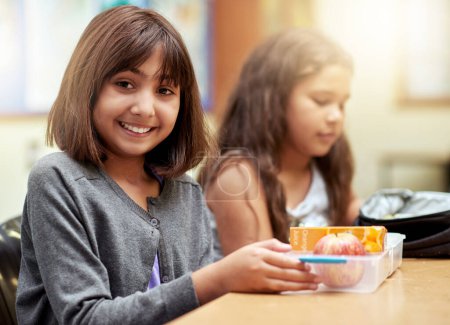 Photo for Girl, smile and portrait with lunch at school for recess, break or nutrition at table with meal. Kid, face and happy at academy or relax with confidence, food and pride for childhood development. - Royalty Free Image