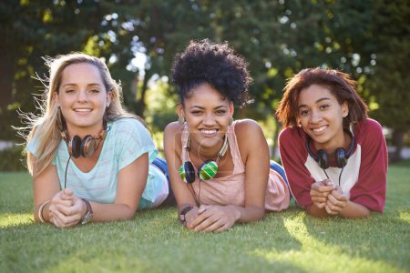 Photo for Grass, portrait or women in park at college, campus or together with community, smile or group. University, relax or happy students bond with support, headphones or diversity in education on field. - Royalty Free Image