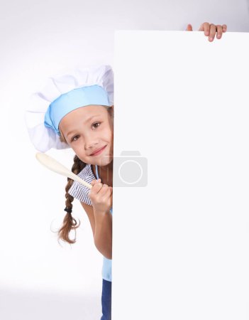 Photo for Child, portrait and chef board space for cooking recipe information, ingredients or instructions. Girl, baker and white background or placard mockup for kitchen review or bakery cake, studio or spoon. - Royalty Free Image