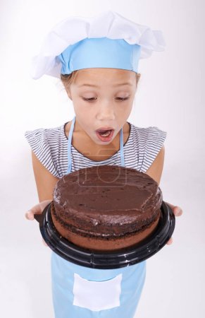 Photo for Kid, baker and shocked with cake, happy and confident with child development on white background. Culinary skills, satisfied and baking dessert and childhood with confidence in hospitality industry. - Royalty Free Image