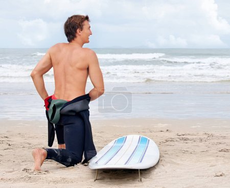 Foto de Surfista, hombre o listo para comenzar en la playa con tabla de surf de vacaciones o aventura para la aptitud o los viajes. Vista trasera de atleta, traje de baño o surf en el mar de vacaciones en Hawái o el océano en deportes extremos. - Imagen libre de derechos