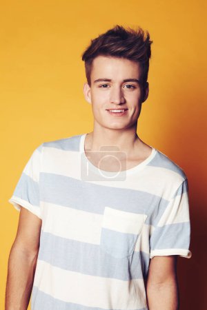 Photo for Portrait, fashion and man with style, smile and confident guy on an orange studio background. Face, person and model with student, casual outfit and stylish clothes with gen z, t shirt and aesthetic. - Royalty Free Image