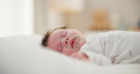 Téléchargez les photos : Fatigué, endormi et nouveau-né sur un lit dans une maison dans la chambre à coucher pour se reposer et rêver. Mignon, doux et petit bébé, enfant ou enfant faire une sieste le matin dans la pépinière à la maison familiale - en image libre de droit