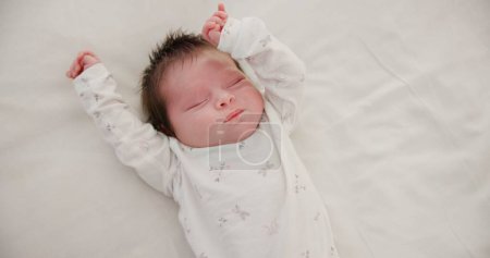 Photo for Newborn, face or sleeping with stretching on bed in nursery for relaxing or resting with child development. Baby, tired or dreaming in bedroom of house with calm, relax and cute infant in family home. - Royalty Free Image
