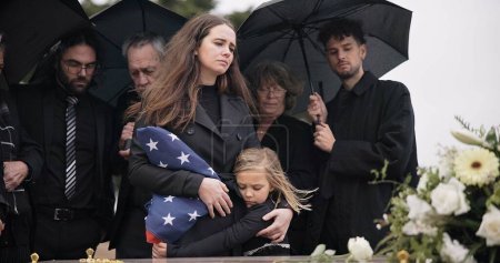 Photo for Funeral, family and sad people with American flag, grief and mourning death, burial and widow depressed at farewell event. Kid, mother and group gathering at coffin, casket and crying at ceremony. - Royalty Free Image