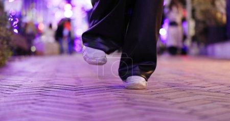 Foto de Primer plano, pies y persona bailando en la calle, moviendo cuerpo o libertad para actuación, ciudad o noche. Chica, bailarina o zapatillas de deporte para el arte, concierto y pasos con creatividad, camino de metro y equilibrio en Tokio. - Imagen libre de derechos