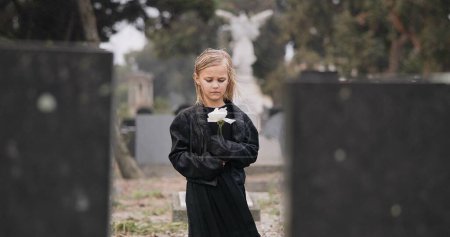 Photo for Flower, death or kid in cemetery for funeral. spiritual service or grave visit for repsect in Christian religion. Mourning, goodbye or sad girl child outside in graveyard for grief, loss or farewell. - Royalty Free Image