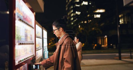 Téléchargez les photos : Distributeur automatique, paiement homme et téléphone la nuit, achat numérique automatique ou choix en ville en plein air. Smartphone, distributeur d'achats et homme d'affaires japonais sur la technologie mobile dans Tokyo urbaine. - en image libre de droit