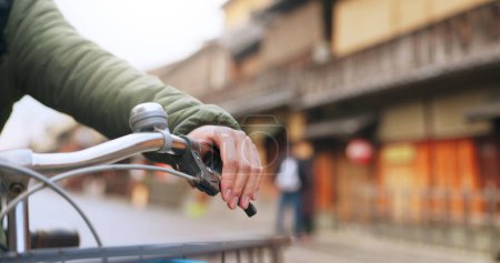 Téléchargez les photos : Mains, vélo et poignée de frein dans la rue, Voyage et transport en plein air du coureur actif sur la route urbaine pour la santé. Gros plan, appuyez sur le guidon et la personne à vélo pour contrôler ou vérifier le vélo à Kyoto Japon. - en image libre de droit