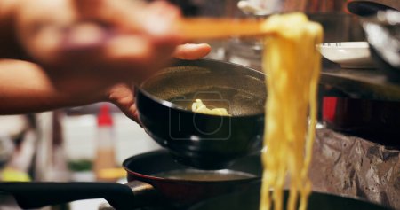 Photo for Cooking, food market and person with noodles on gas stove for meal preparation, eating and restaurant. Japanese culinary, flame and closeup of chopsticks to prepare lunch, cuisine dinner and supper. - Royalty Free Image
