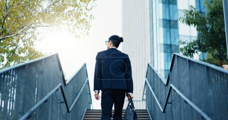 Photo for Stairs, walking and back of businessman in the city by office building for travel with career. Outdoor, energy and professional male person commuting on steps to modern workplace in urban town - Royalty Free Image