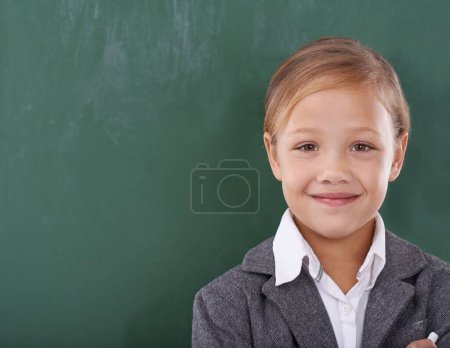 Photo for Child, portrait and chalkboard for school learning in classroom for education, writing or homework. Female person, uniform and kindergarten development or brainstorming or knowledge, growth or mockup. - Royalty Free Image