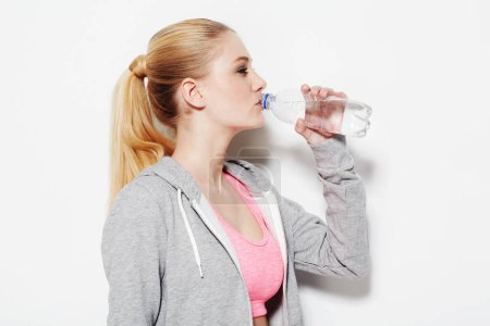 Photo for Woman, drinking water and workout in studio profile, thinking and vision for fitness by white background. Girl, model and person with bottle, liquid and hydration for detox, wellness and nutrition. - Royalty Free Image