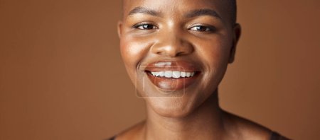 Téléchargez les photos : Visage, soin de la peau et sourire avec une heureuse femme noire en studio isolée sur fond brun pour le bien-être. Portrait, beauté et esthétique pour fond de teint cosmétique ou dermatologie avec un jeune homme naturel. - en image libre de droit