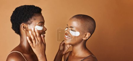 Téléchargez les photos : Beauté, protège-yeux et visage de femmes noires en studio avec une routine éclatante, naturelle et faciale. Sourire, soins de la peau et portrait d'amies africaines avec traitement cosmétique sur fond brun - en image libre de droit
