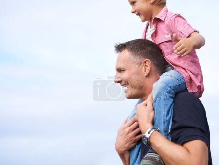 Photo for Father, outdoor and carrying son on shoulders for childhood playing, sunshine and wellness by blue sky. Parent, child and happiness in nature for bonding together, love and fun on outside on vacation. - Royalty Free Image