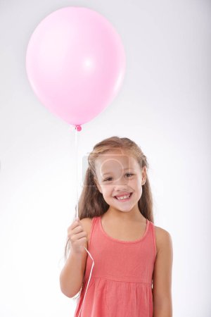 Photo for Girl, child and balloon in portrait, party decoration and smiling for milestone event in studio. Happy female person, inflatable accessory and birthday joy on white background, playful and celebrate. - Royalty Free Image