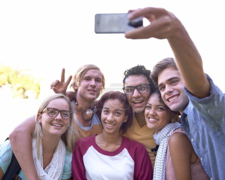 Foto de Estudiantes, selfie y celular en el campus con sonrisa, juntos y bienestar en la universidad para publicación en línea. Amigos, teléfonos inteligentes o diversidad en la educación o grupo de estudio en la foto de perfil al aire libre. - Imagen libre de derechos