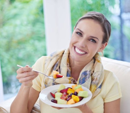 Téléchargez les photos : Alimentation saine, femme en portrait avec salade de fruits et régime alimentaire, produits biologiques et se détendre sur le canapé avec le sourire pour la perte de poids. Repas végétalien, santé intestinale et bien-être, manger pour la nutrition avec des vitamines. - en image libre de droit