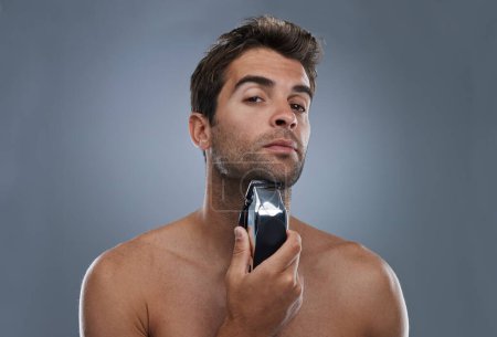 Photo for Man, shaving and electric razor in studio portrait for grooming, skincare and wellness by grey background. Person, model and beard with hygiene, facial hair removal and product for cosmetic change. - Royalty Free Image