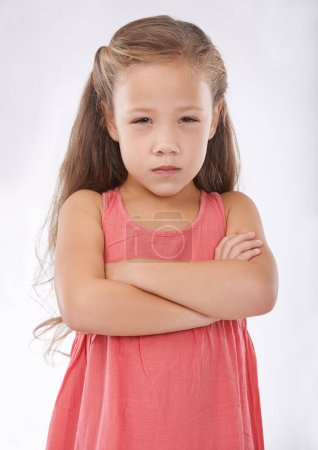 Photo for Angry, girl and child in studio with arms crossed, frustrated in portrait and emotion, cross or upset on white background. Facial expression, rage and conflict with tantrum, furious and bad attitude. - Royalty Free Image