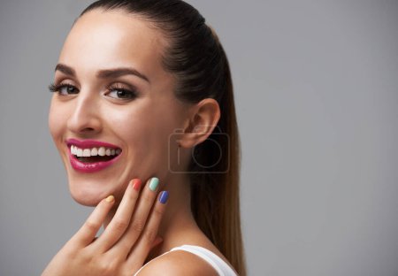 Photo for Happy woman, portrait and manicure with pink lipstick for beauty, rainbow nail polish and cosmetics on grey background. Cosmetology, lips and color nails with makeup, confidence and glamour in studio. - Royalty Free Image