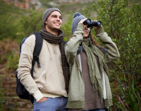 Photo for Couple, travel and binoculars in nature for hiking, adventure and journey or explore together in winter. Happy man and woman trekking with outdoor search, vision or birdwatching in forest or woods. - Royalty Free Image