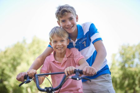 Téléchargez les photos : Nature, heureux et portrait d'enfants en vélo dans un terrain extérieur, parc ou forêt pour l'exercice. Sourire, vélo et jeunes enfants confiants à vélo pour le cardio, le passe-temps ou l'entraînement dans un jardin - en image libre de droit