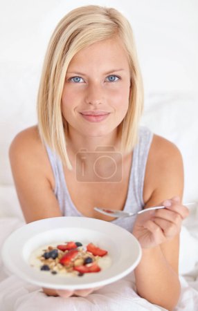 Photo for Breakfast, portrait and woman in a bed with muesli, meal or berries for balance, wellness or gut health at home. Fruit, eating or female person face in bedroom for diet, nutrition or superfoods snack. - Royalty Free Image