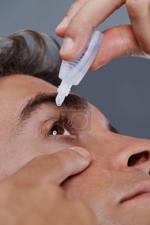 Photo for Man, eye drops and vision for allergies or treatment in studio or healthcare wellness, dropper or grey background. Male person, solution and conjunctivitis for clean pupil or pain, liquid or apply. - Royalty Free Image