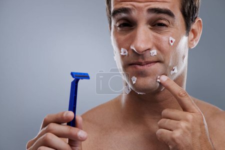 Photo for Man, face and shave cuts or pain for hair removal or hygiene injury with blood, tissue or maintenance. Male person, grey background and dermatology with beard or clean health, studio or mockup space. - Royalty Free Image